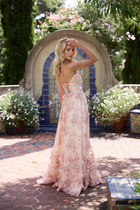 Back view of a light pink floral tiered maxi dress with a lace-up corset back and ruffled skirt.