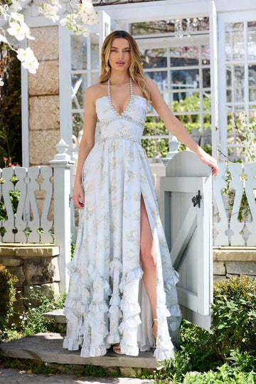 Light blue floral tiered maxi dress with pearl trim, high slit, and ruffled skirt in an outdoor garden.