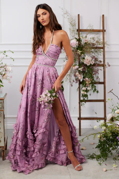 Purple floral tiered maxi dress with pearl halter neckline and side slit, featuring ruffled skirt details.
