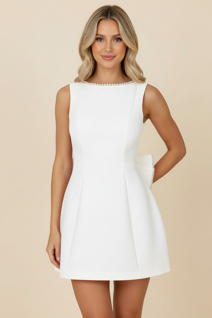 Front view of a white sleeveless mini dress featuring a pearl-embellished neckline and a back bow.