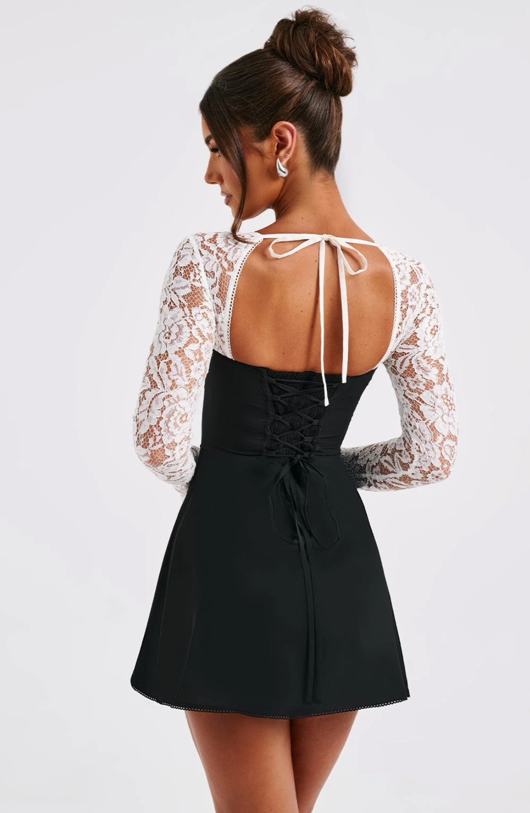 Back view of the black Gemma Tie Mini Dress, highlighting the white lace sleeves and corset lacing.