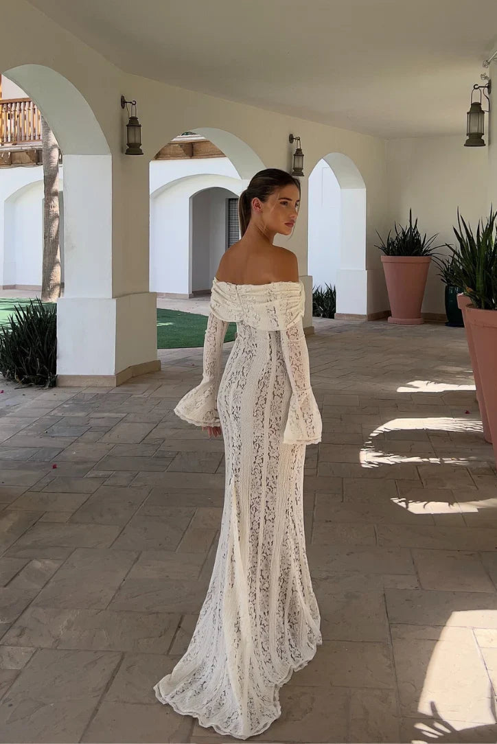 Back view of the white lace maxi dress, featuring a fitted silhouette and a slight train, on a patio.