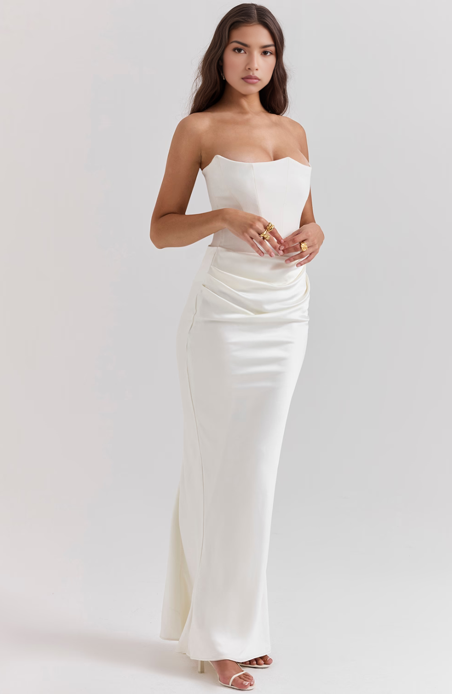 Three-quarter view of a woman in a white corset maxi dress, showing the sweetheart neckline and stylish ruched waist detail.