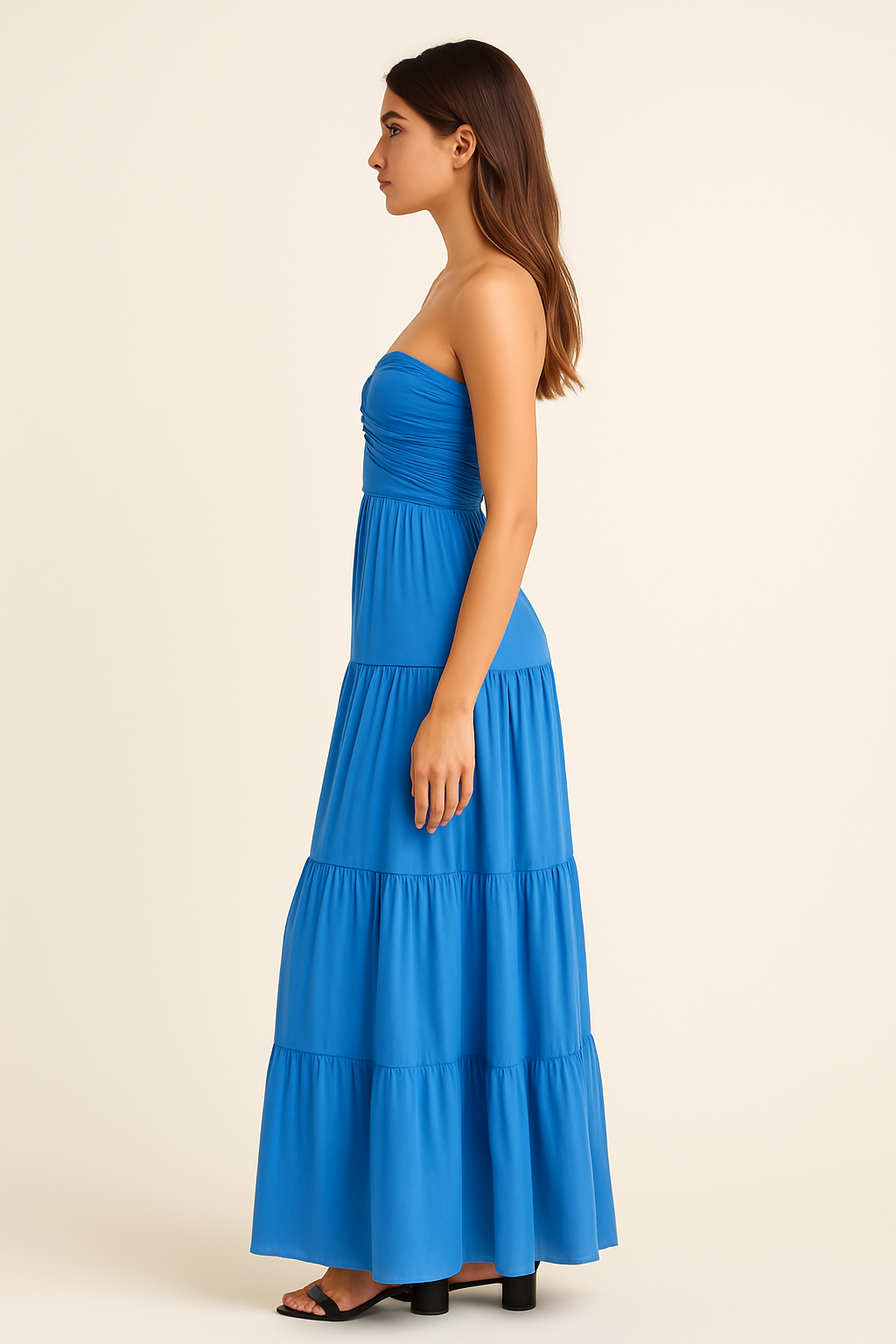 Side view of a woman wearing a blue strapless ruched bodice tiered maxi dress