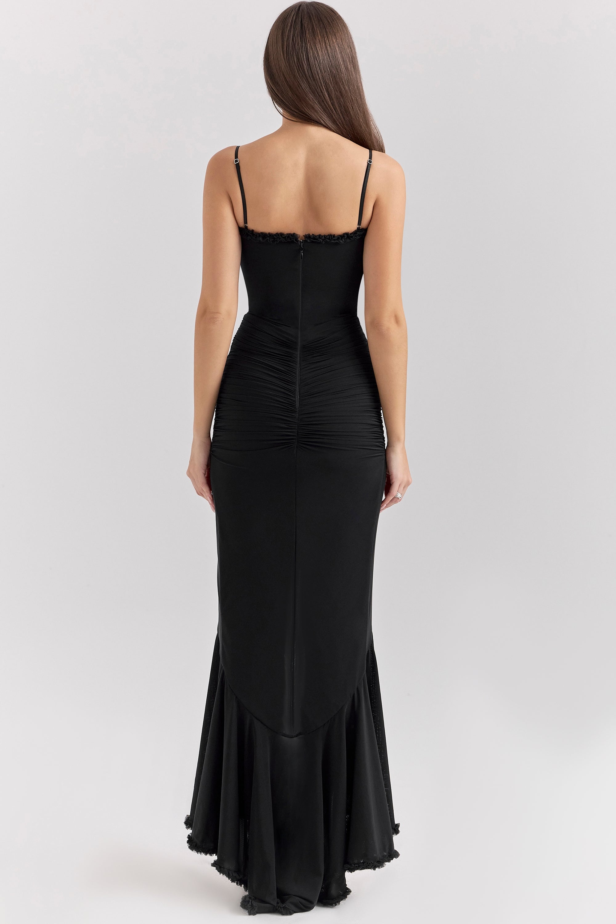 Back view of a woman wearing a black Isla Ruffle Maxi Dress, showing the spaghetti straps and ruched detailing on the back.