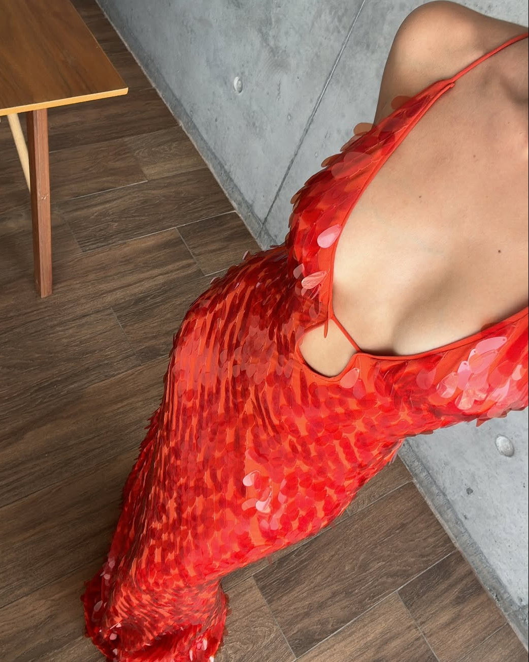 Close-up detail of the red sequin maxi dress, showcasing the shimmering sequins and the plunging neckline with a delicate cut-out.