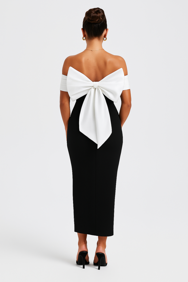 Back view of a black midi dress featuring a large white oversized bow detail, off-the-shoulder design, and fitted skirt.