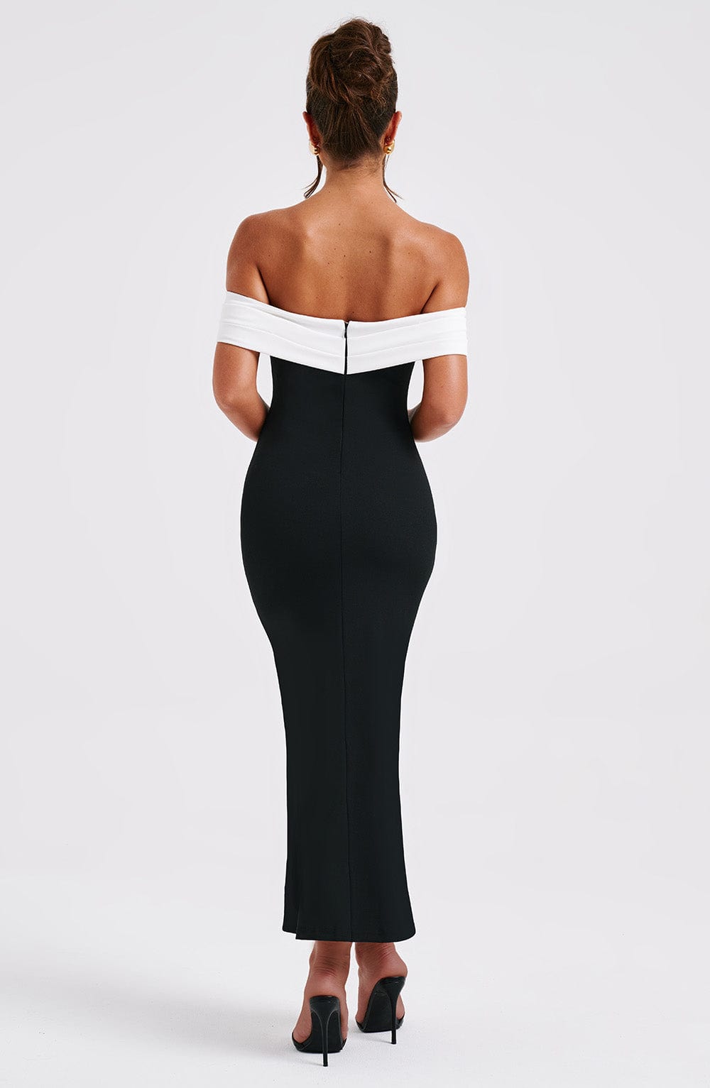 Full back view of a black off-the-shoulder midi dress, showing the white neckline detail and the sleek, tailored silhouette.