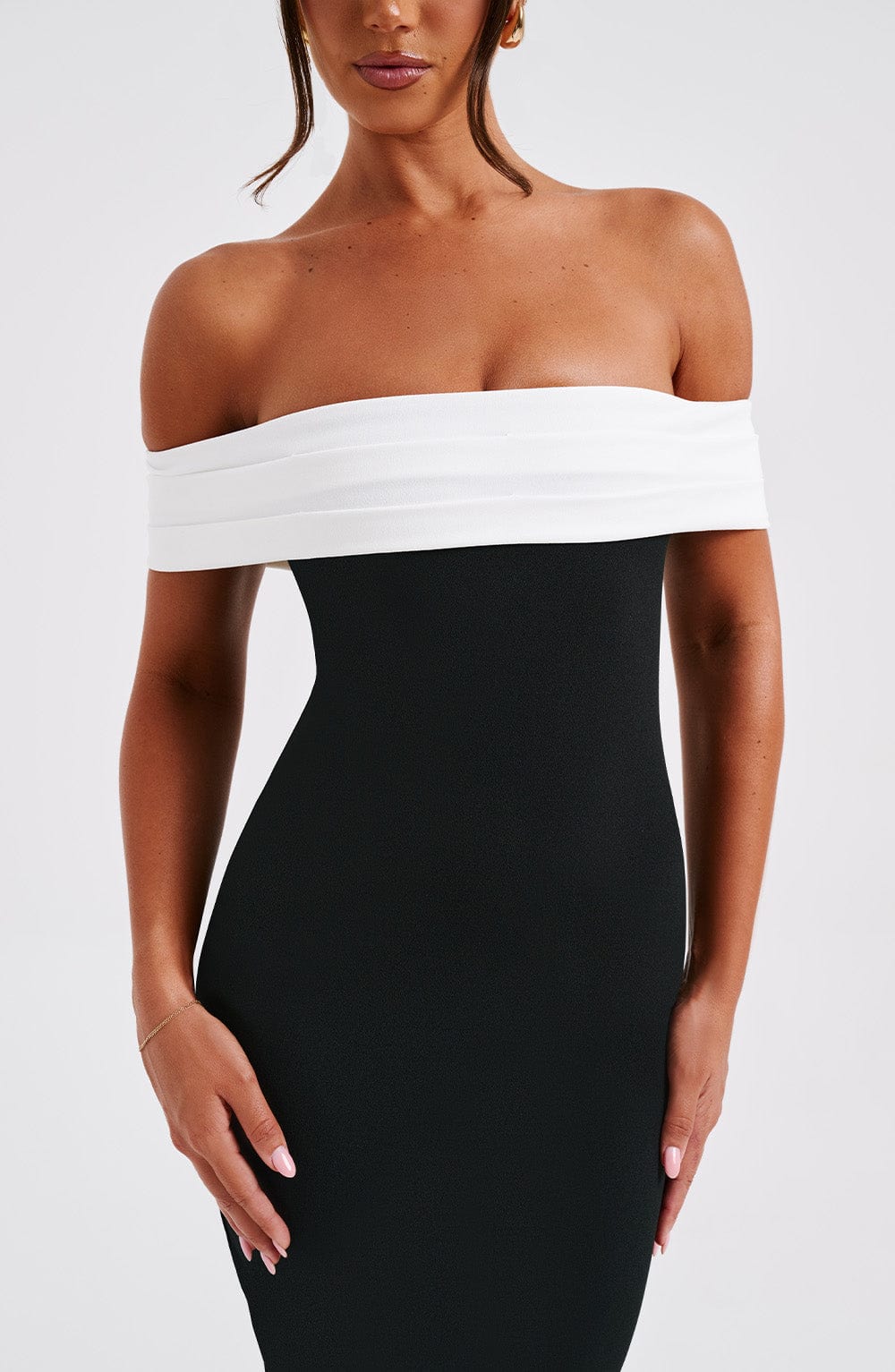 Close-up of the bodice of a black off-the-shoulder midi dress, detailing the white folded neckline and the textured fabric.