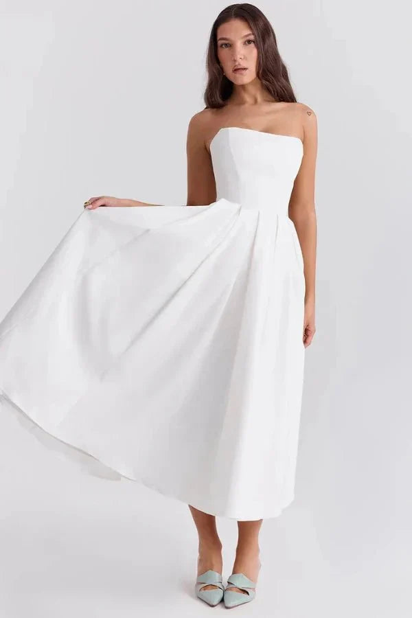 White strapless midi dress with a flowing A-line skirt, shown with light blue pointed-toe heels, perfect for a dress suit.