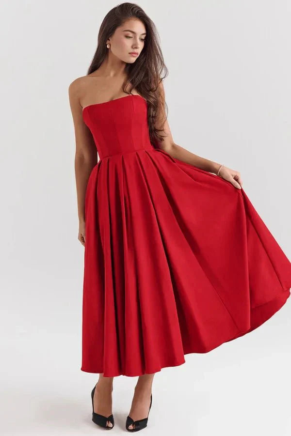 Front view of a red strapless midi dress with a voluminous pleated skirt, paired with black open-toe heels, a striking suit dress.