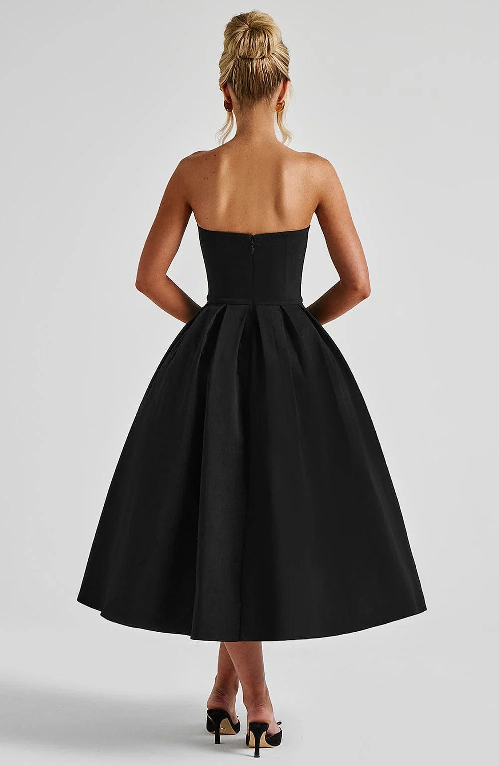 Back view of the black strapless midi dress, highlighting the elegant silhouette and pleated skirt.