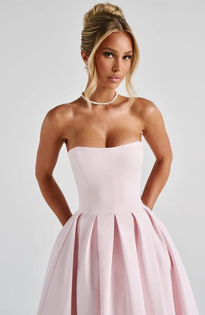 Close-up of the light pink strapless midi dress, showing the bodice, pleats, and a pearl necklace.