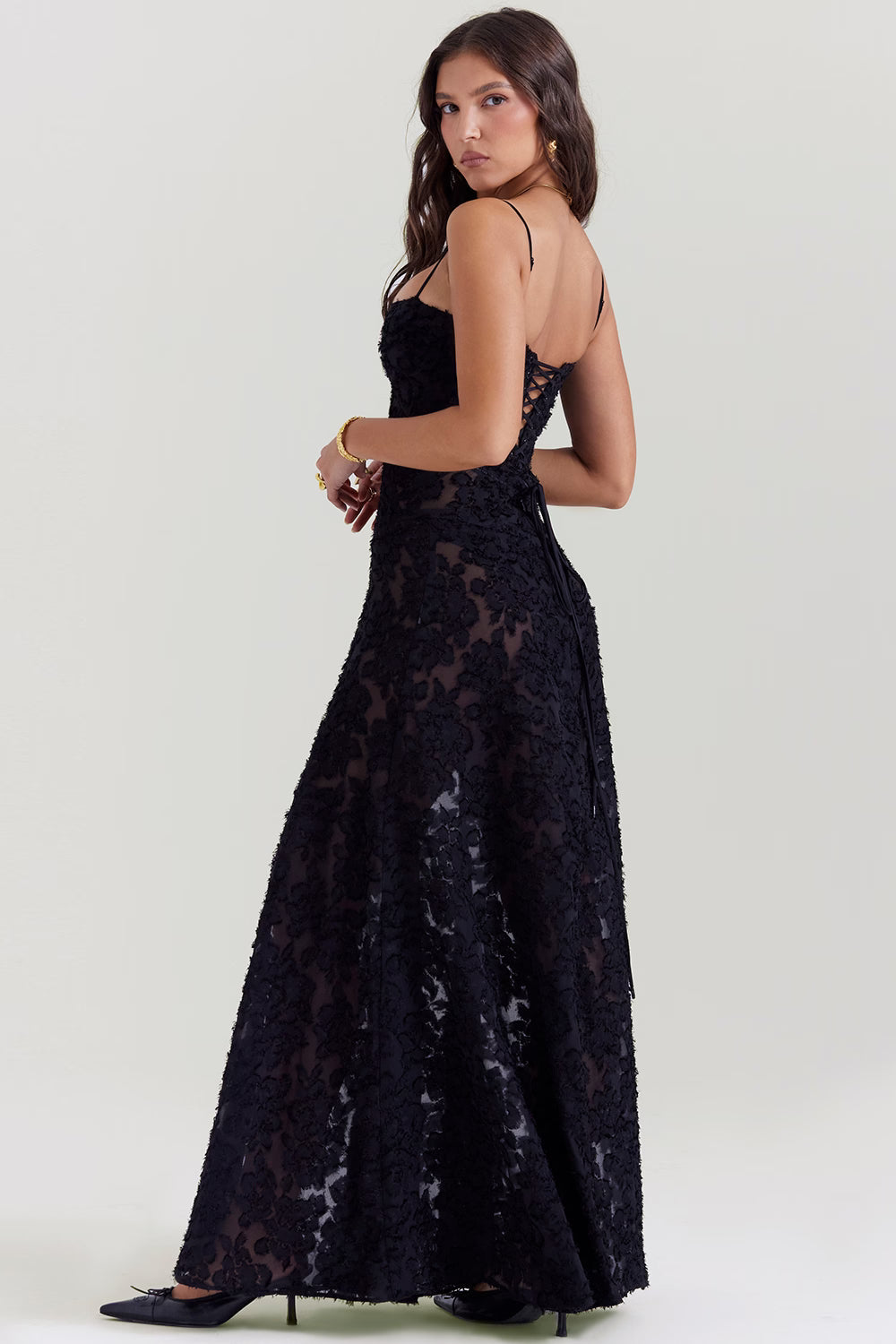 Side profile of the black Juliet Lace Maxi Dress, revealing the elegant lace-up corset back and flowing skirt.