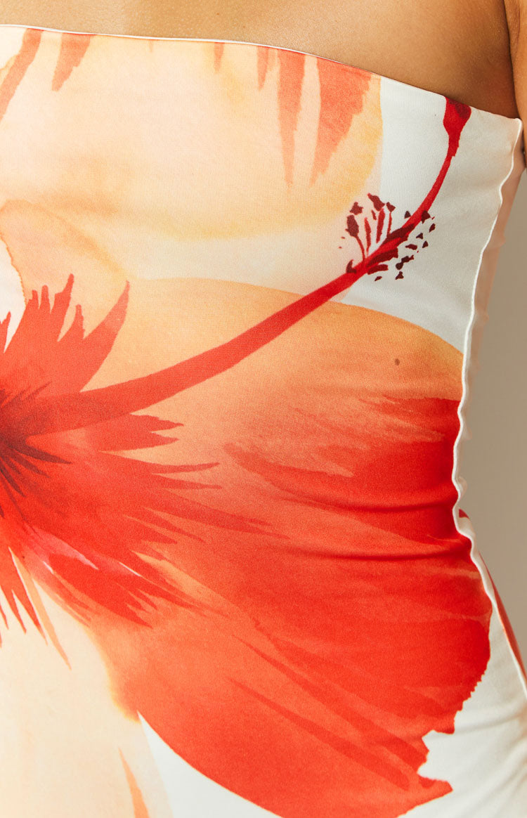 Close-up detail of the vibrant red and orange hibiscus print on the white dress fabric