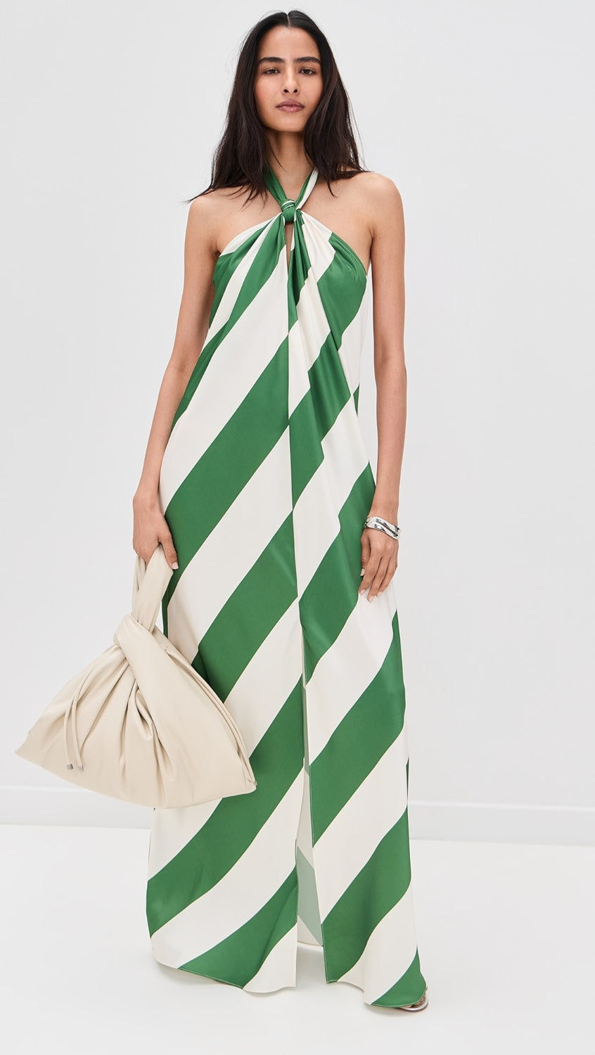Full-length June Stripe Maxi Dress in green and white with halter neckline and front slit, paired with a cream clutch.