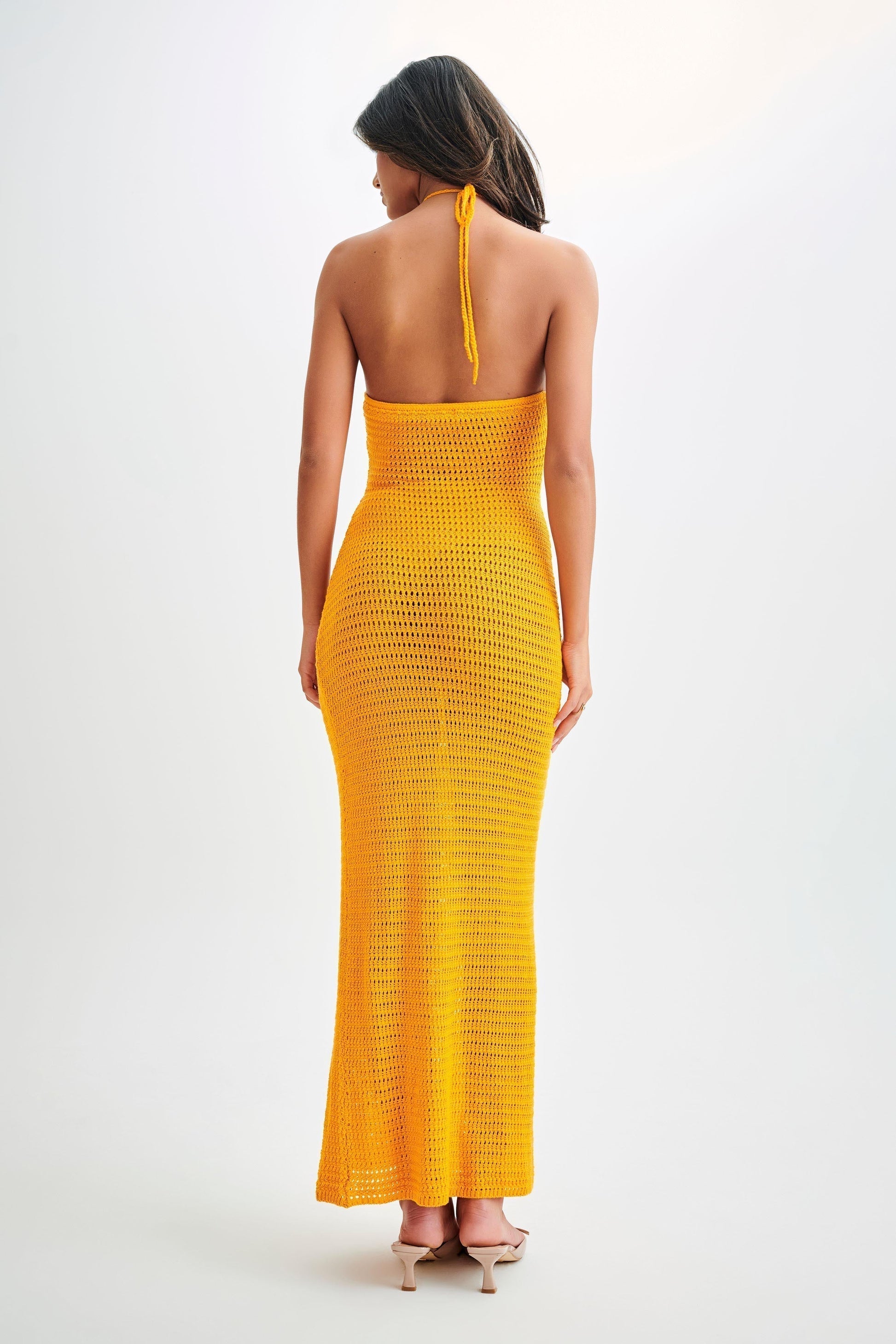 Back view of a yellow crochet maxi dress with a halter tie closure and a form-fitting silhouette, a stylish dress for women.