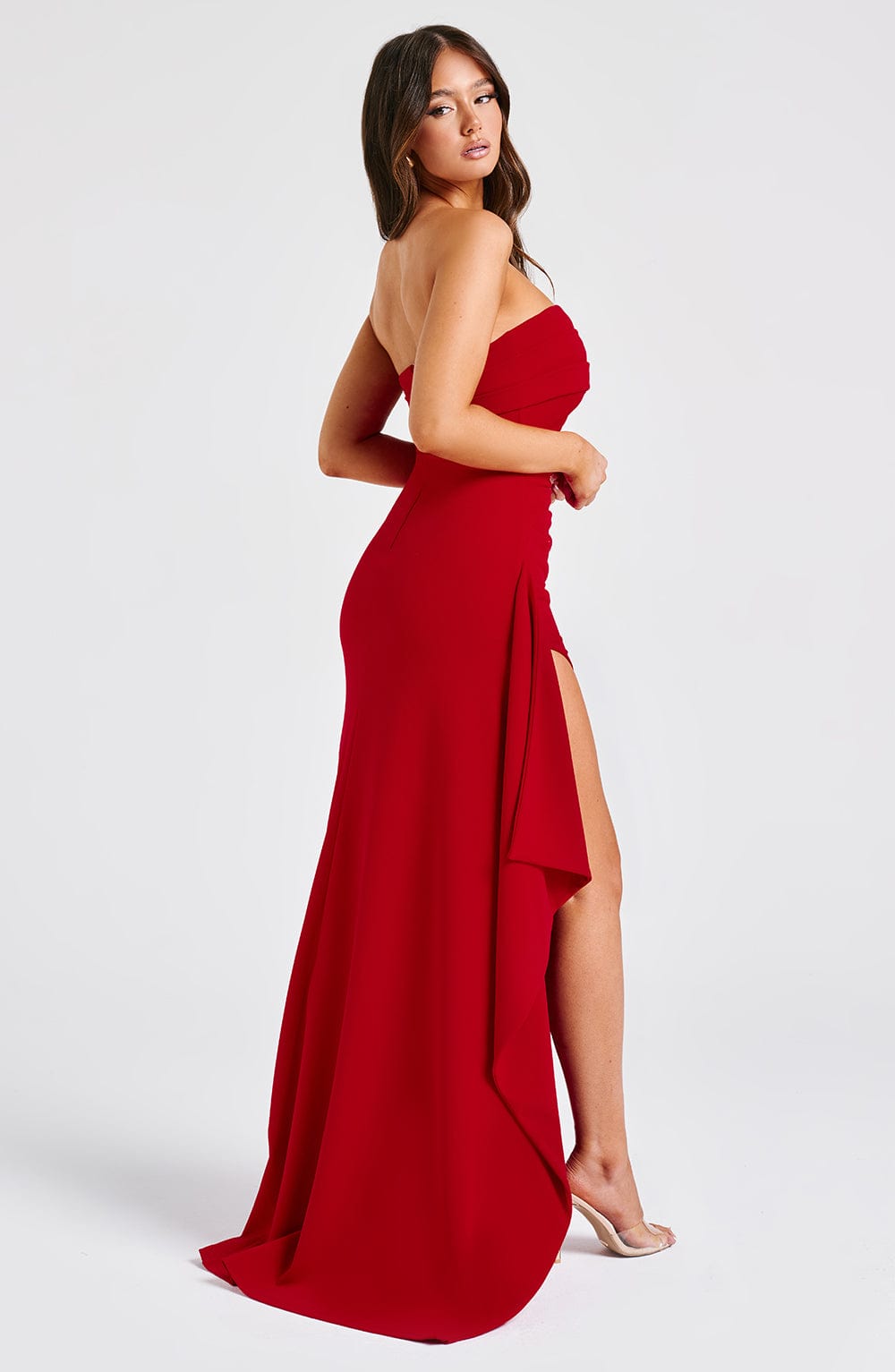 Angled view of the flowing red Kyla Draped Maxi Dress, showcasing the long train and the dramatic thigh-high slit.