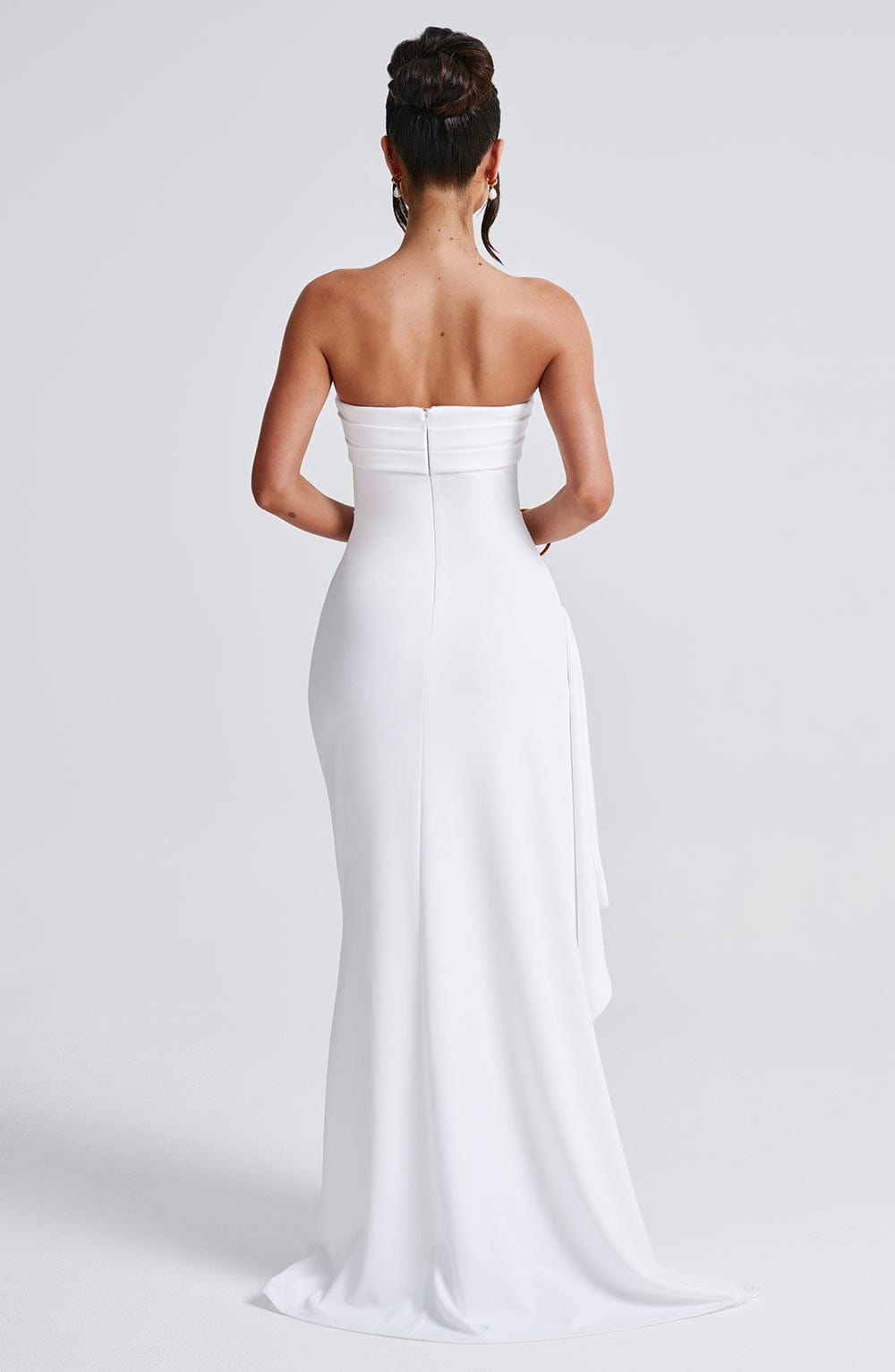 Back view of a white strapless maxi dress, revealing a subtle zipper closure and flowing train.