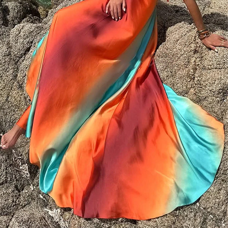 View of the flowing skirt of the Kylie Cutout Maxi Dress, displaying the full breadth of the colorful ombre fabric as it drapes on rocks.