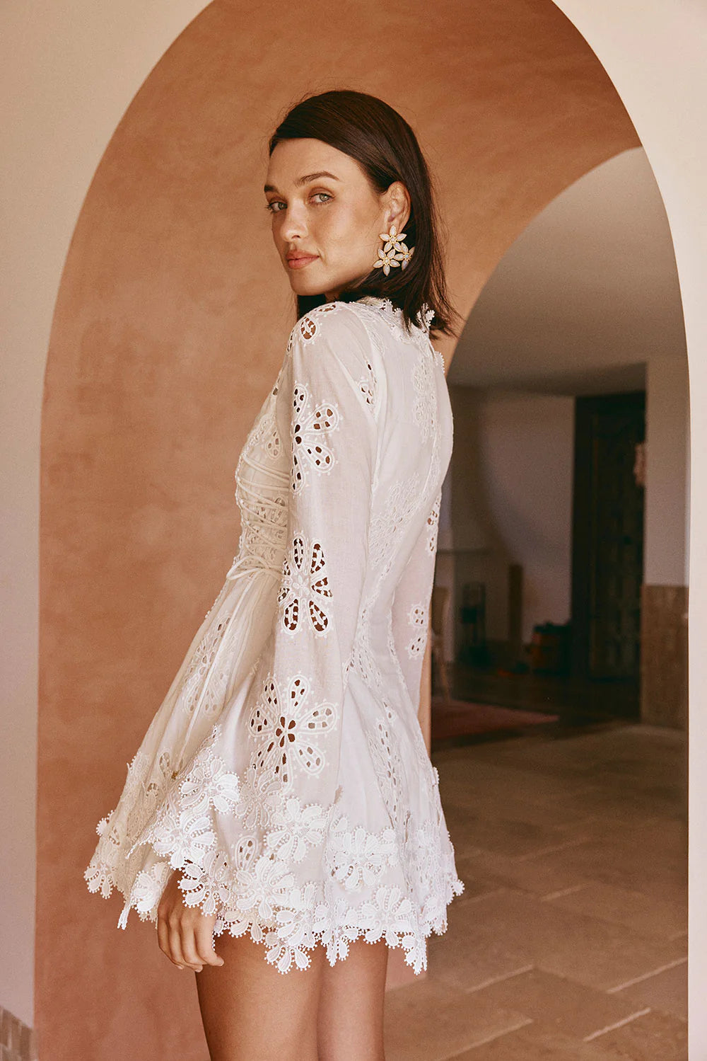 Rear view of the white lace scalloped mini dress, highlighting the detailed back and the flowy skirt with a scalloped edge.