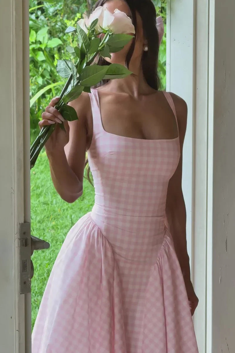 Close-up of a woman in a pink gingham Lana Midi Dress holding white roses, showing the square neckline detail.