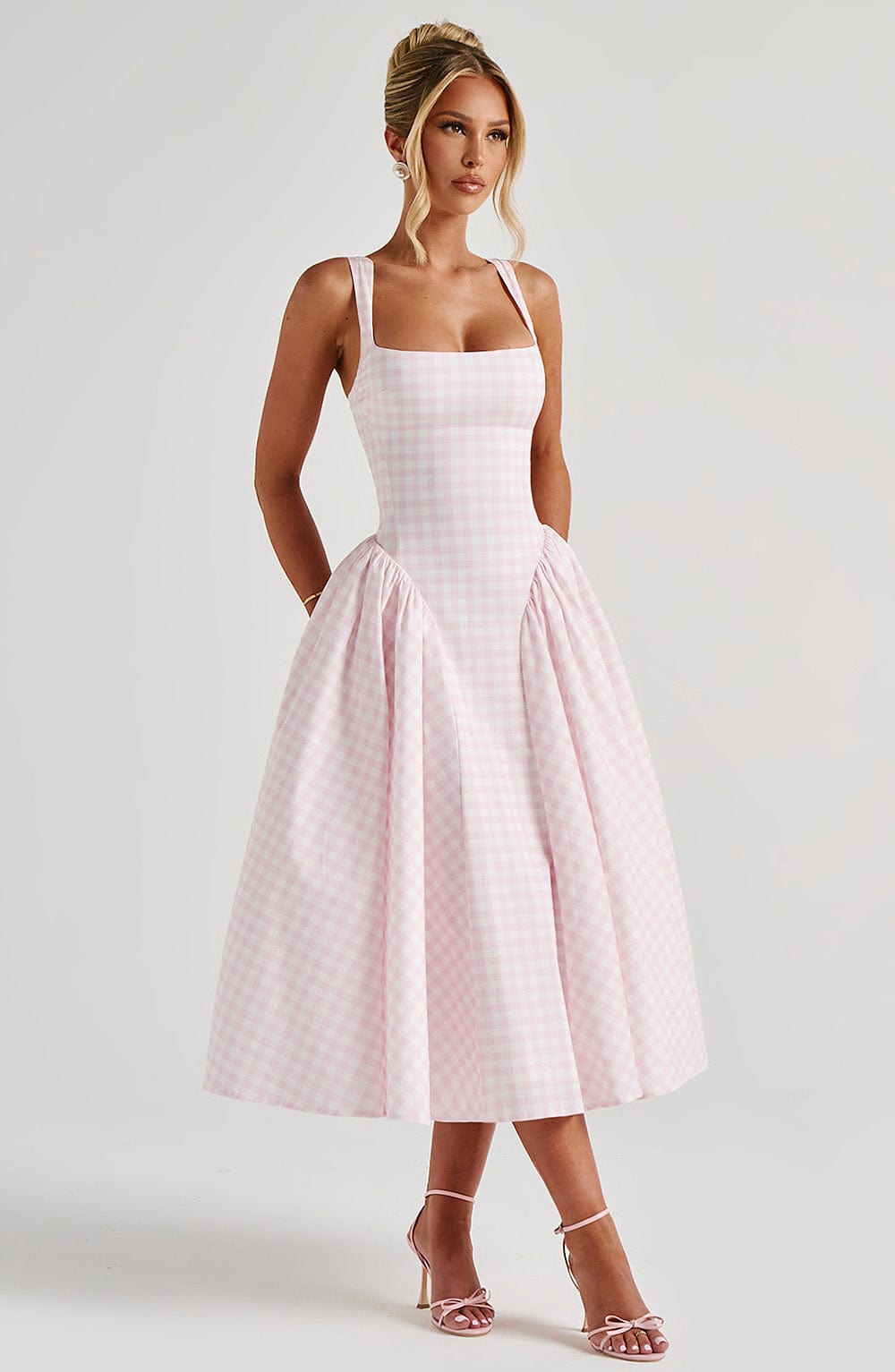 Woman in a light pink gingham Lana Midi Dress with a fitted bodice, square neckline, and full midi skirt.