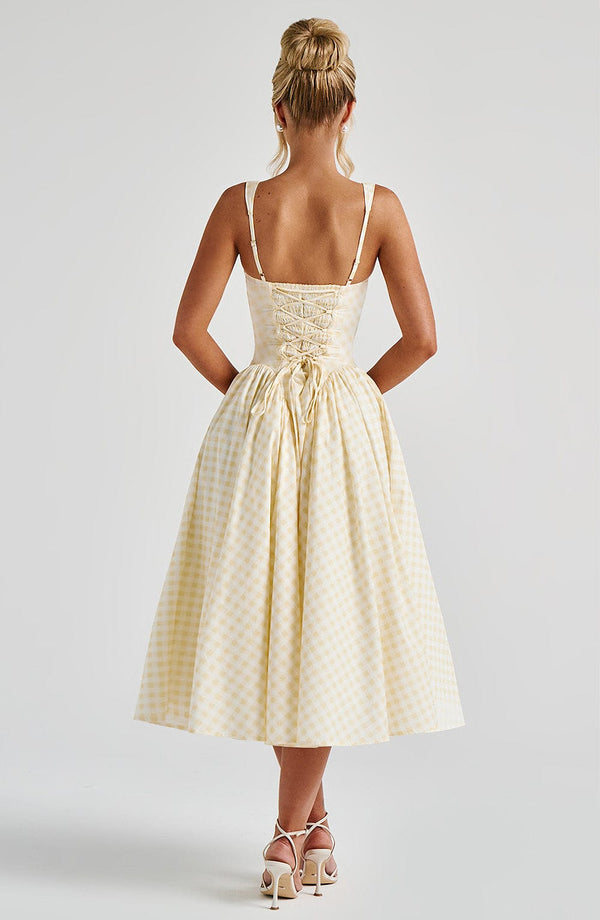 Back view of the light yellow gingham Lana Midi Dress, showing the delicate lace-up back and full skirt.