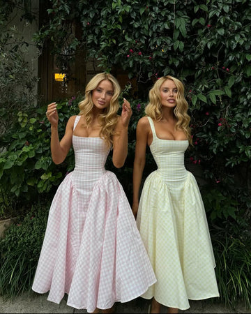 Two women wearing Lana Gingham Midi Dresses, one in pink gingham and one in light yellow gingham, with full skirts.
