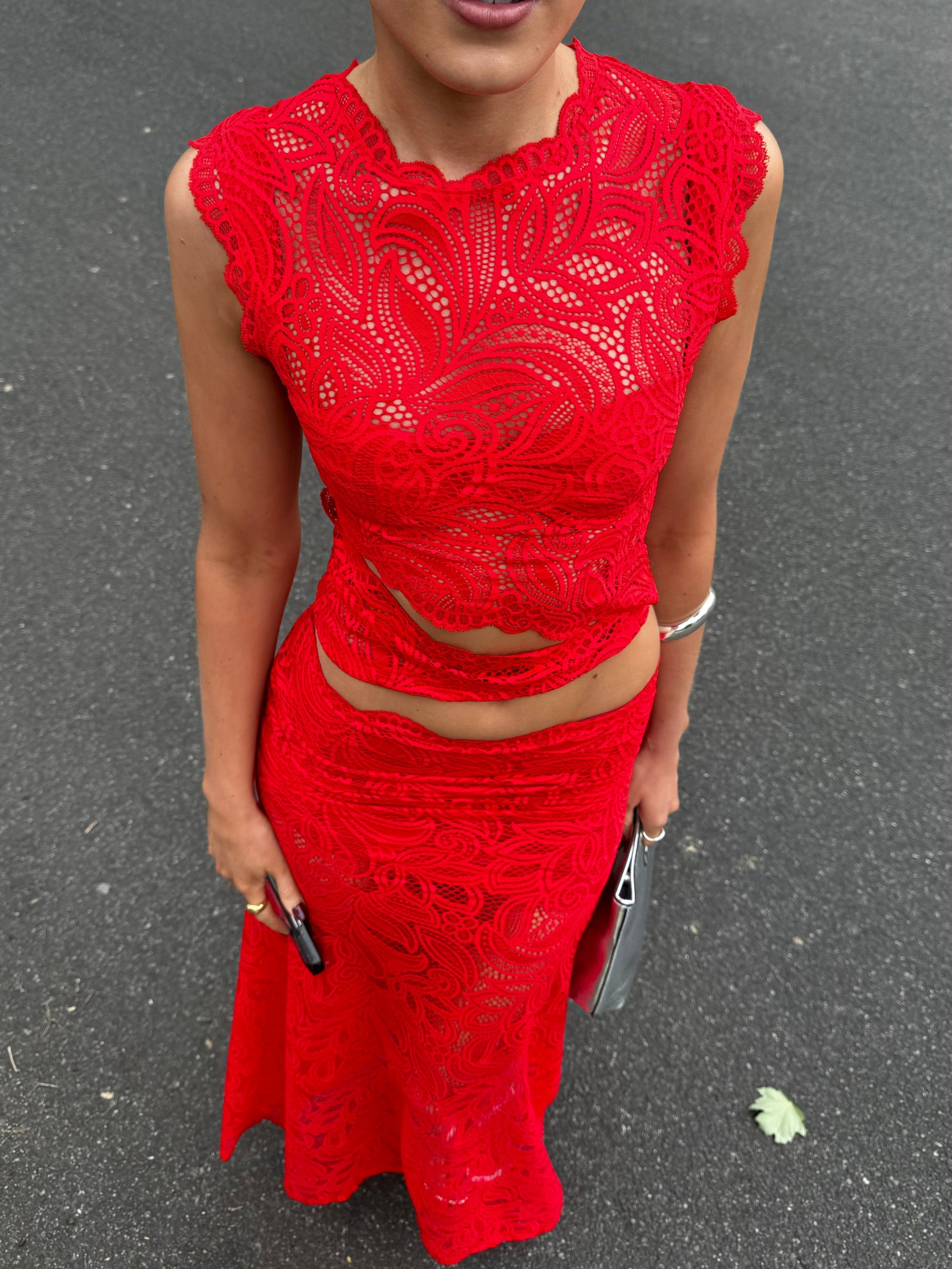 Full body shot of a woman in a bright red lace maxi dress set, featuring a sleeveless top and long skirt.