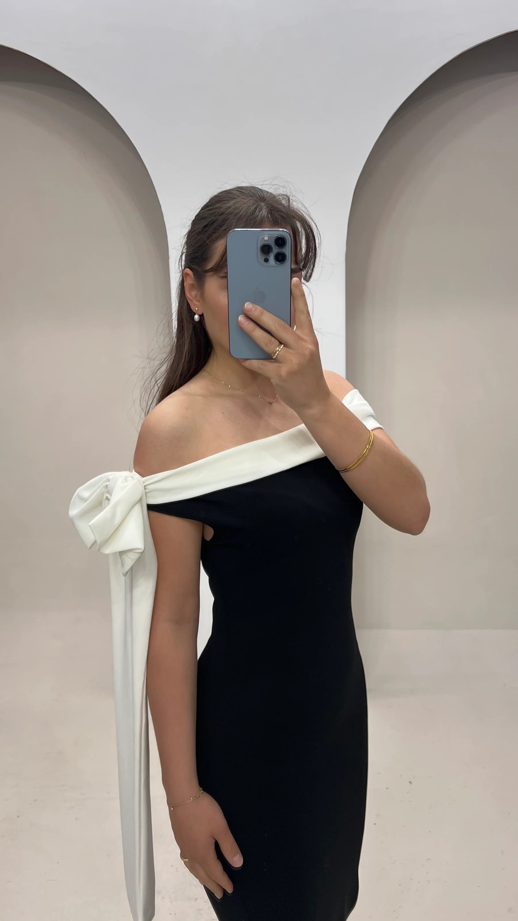 Close-up of black off-shoulder maxi dress showing white trim and large white bow detail on shoulder for women