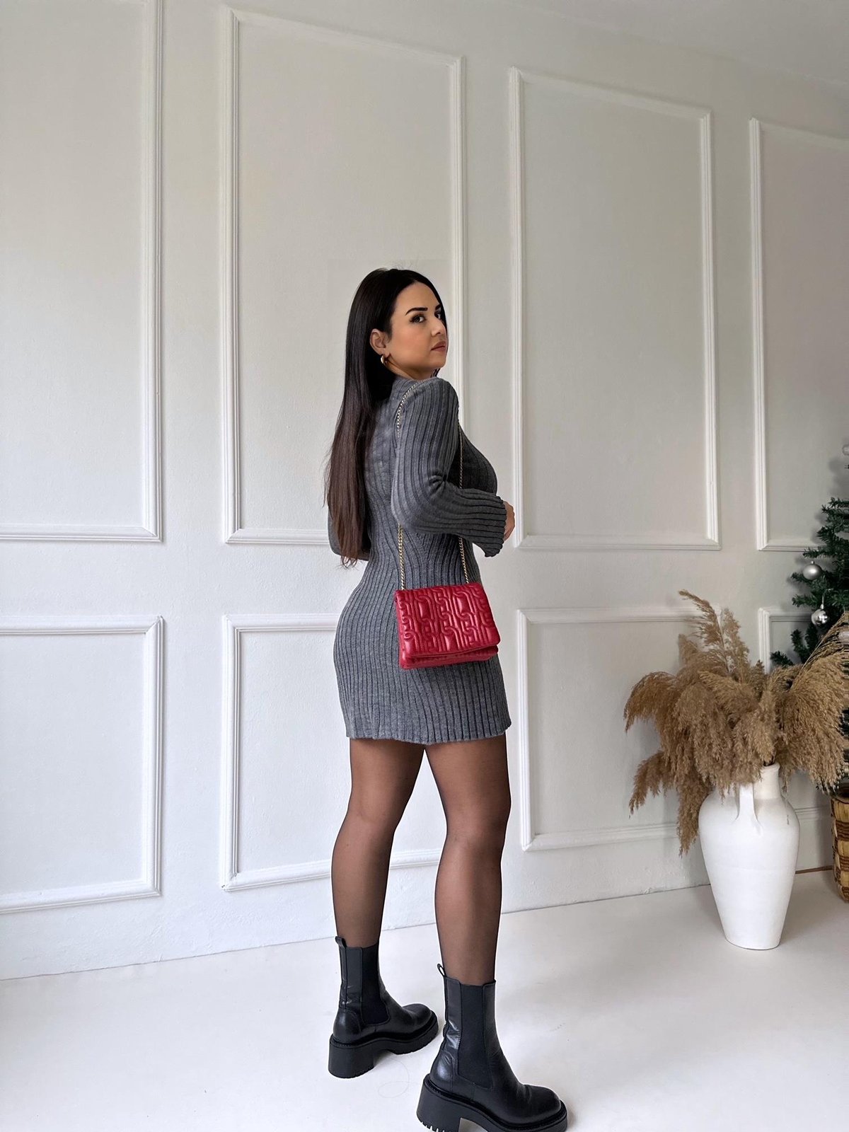 Back view of a dark grey ribbed knit mini dress, showcasing the fitted silhouette and long sleeves, with black tights and boots.