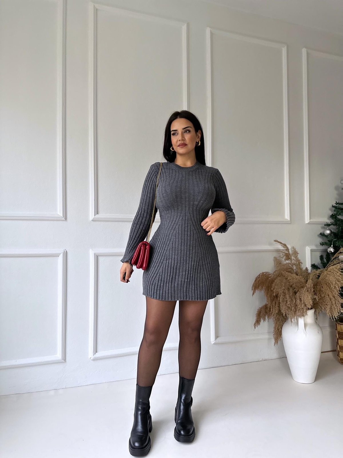 Dark grey ribbed knit mini dress with long sleeves, paired with black tights and combat boots, holding a red handbag.