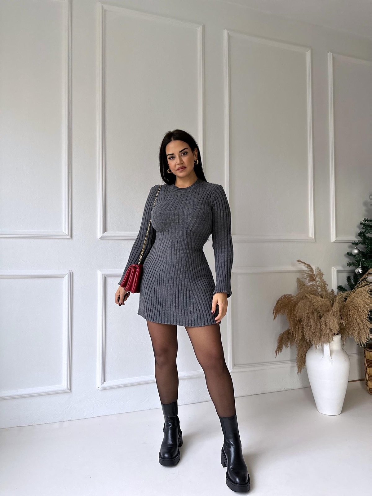 Front view of a dark grey ribbed knit mini dress with long sleeves, styled with black tights and chunky black boots.
