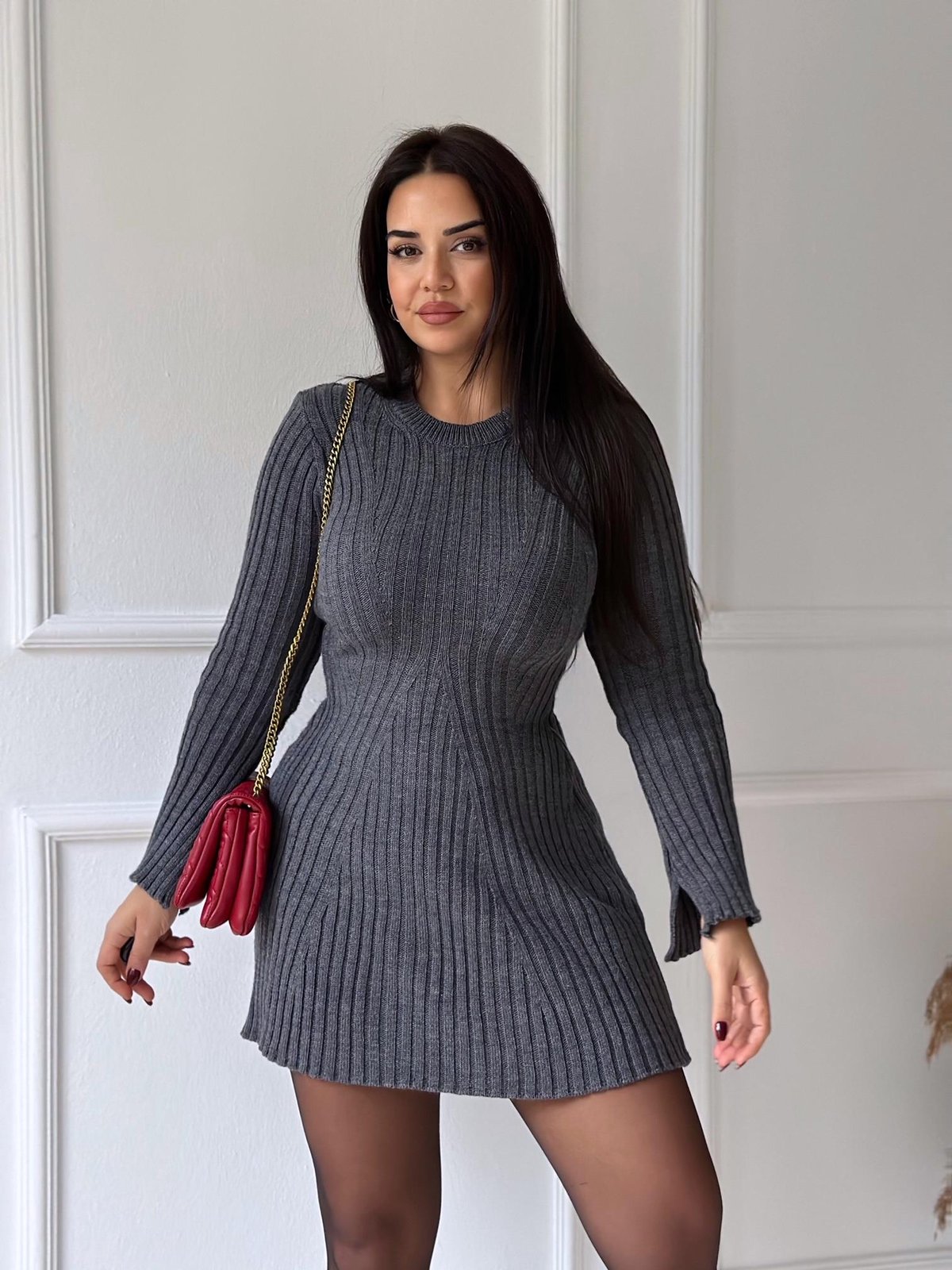 Dark grey ribbed knit mini dress with long sleeves and a round neck, featuring a subtle A-line skirt, holding a red bag.