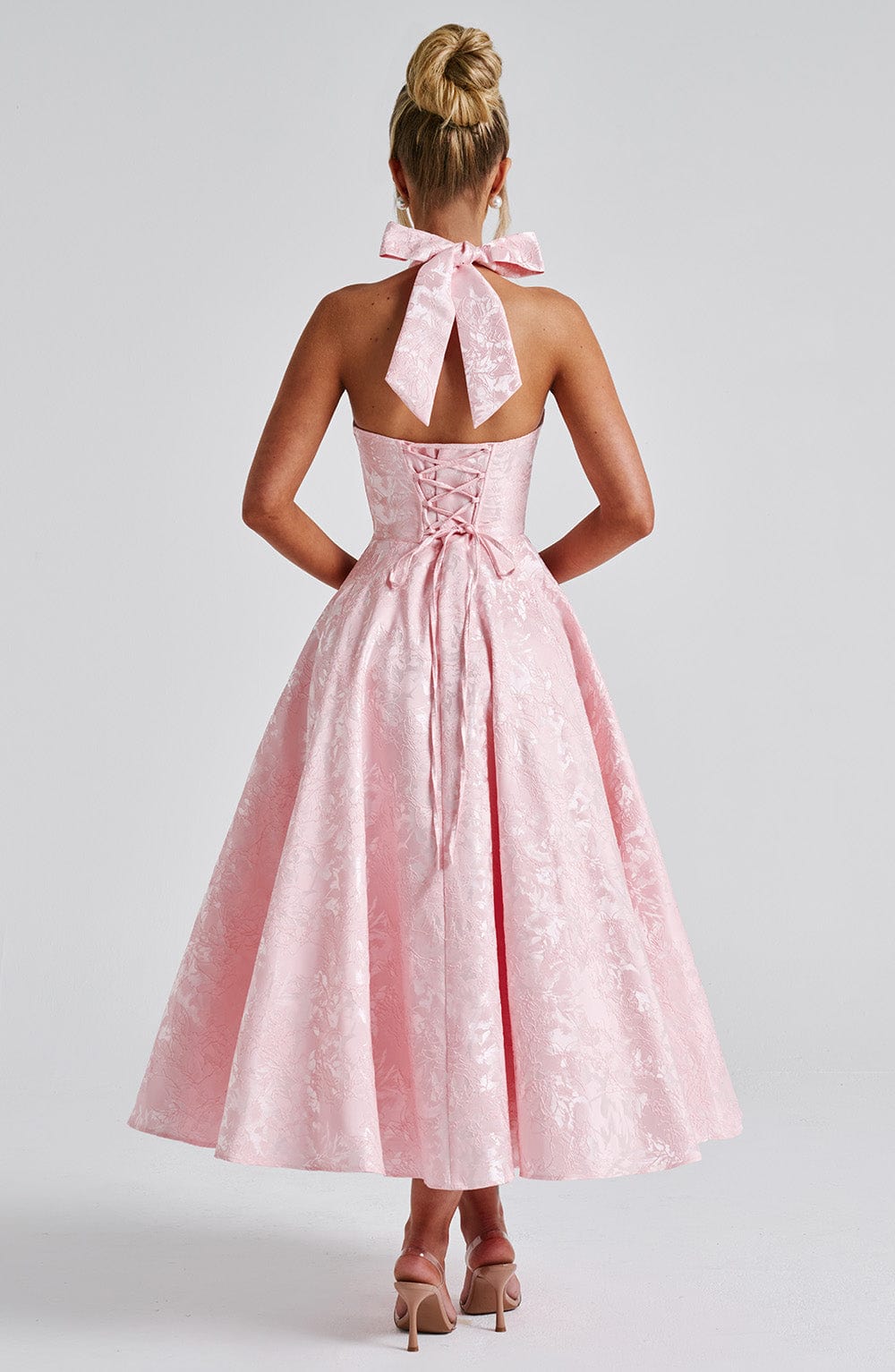 Rear view of the light pink Leilani halter midi dress, displaying the bow-tie halter and corset back detail.