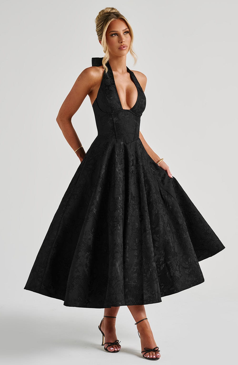 Black Leilani Halter Midi Dress with a full A-line skirt and subtle floral texture, shown with model posing.
