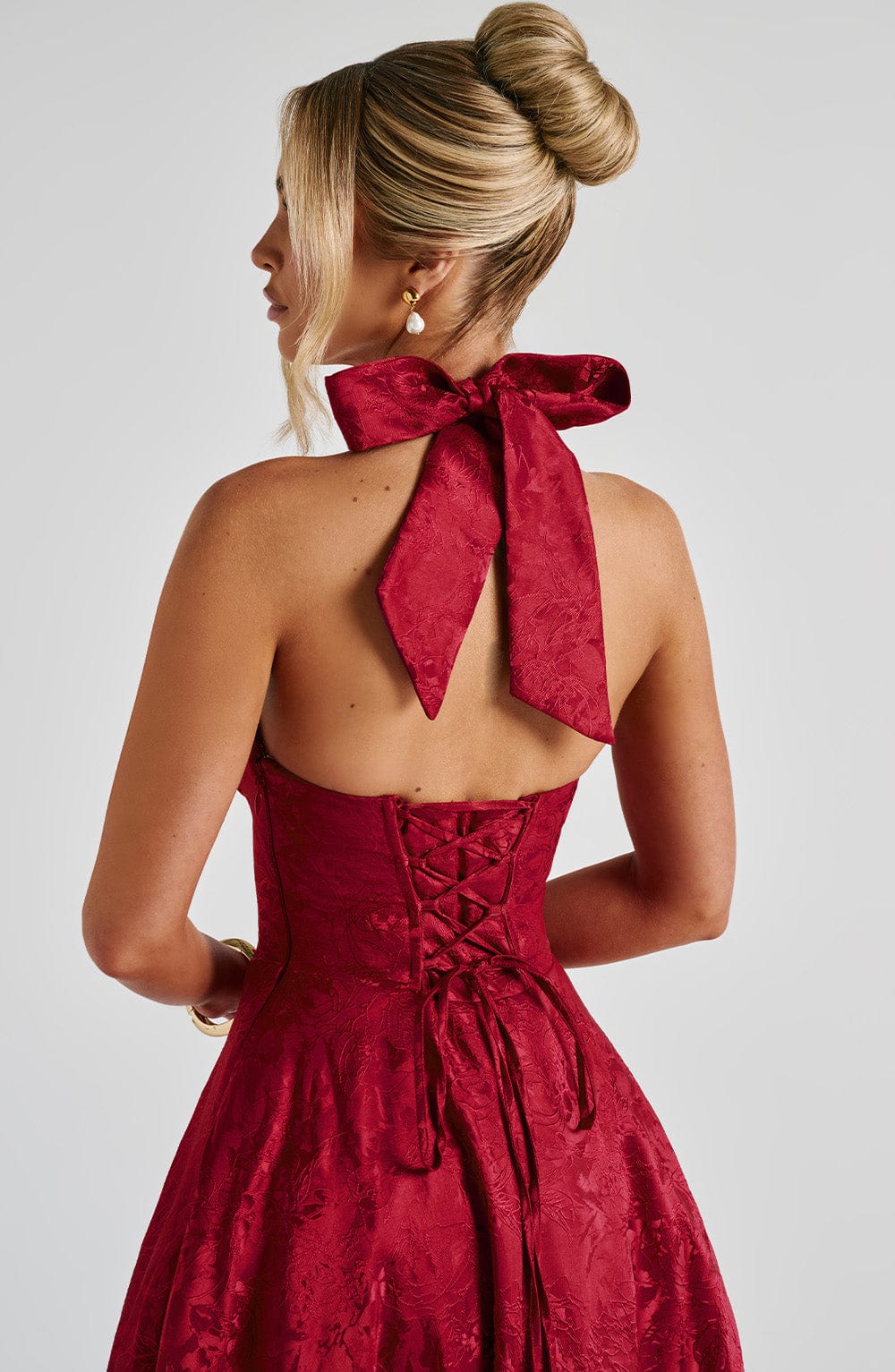 Rear close-up of the red Leilani Halter Midi Dress, focusing on the ornate bow and corset back details.