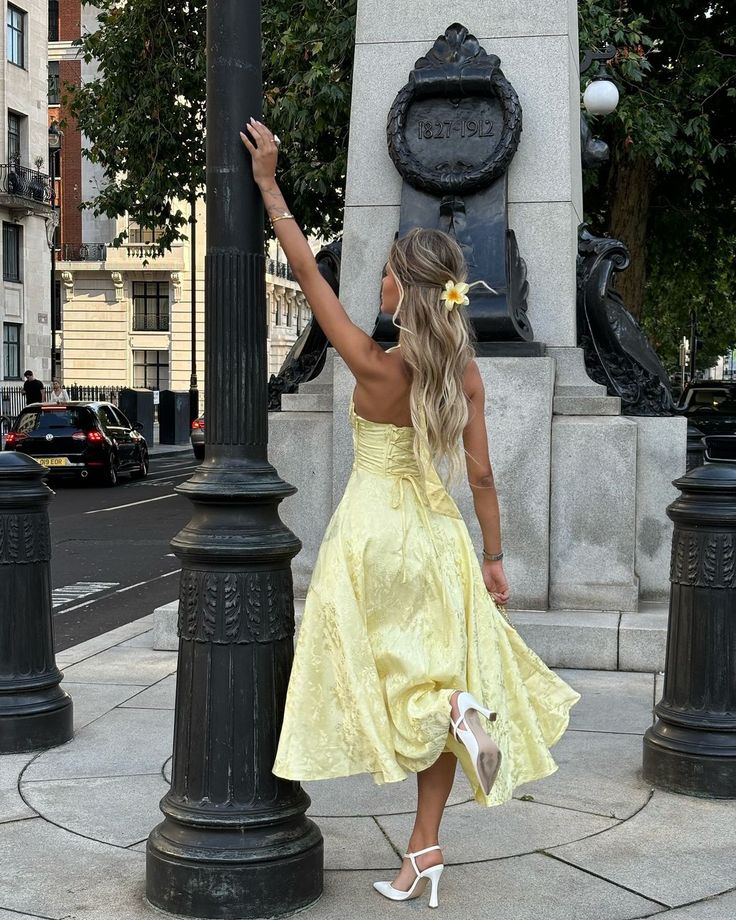 Back view of the Leilani halter midi dress in light yellow, showing the lace-up corset detail and full skirt.