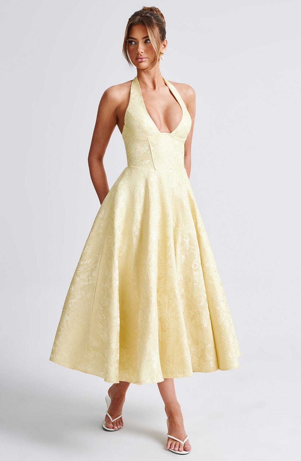 Full-length studio shot of the Leilani halter midi dress in light yellow, highlighting the elegant silhouette.