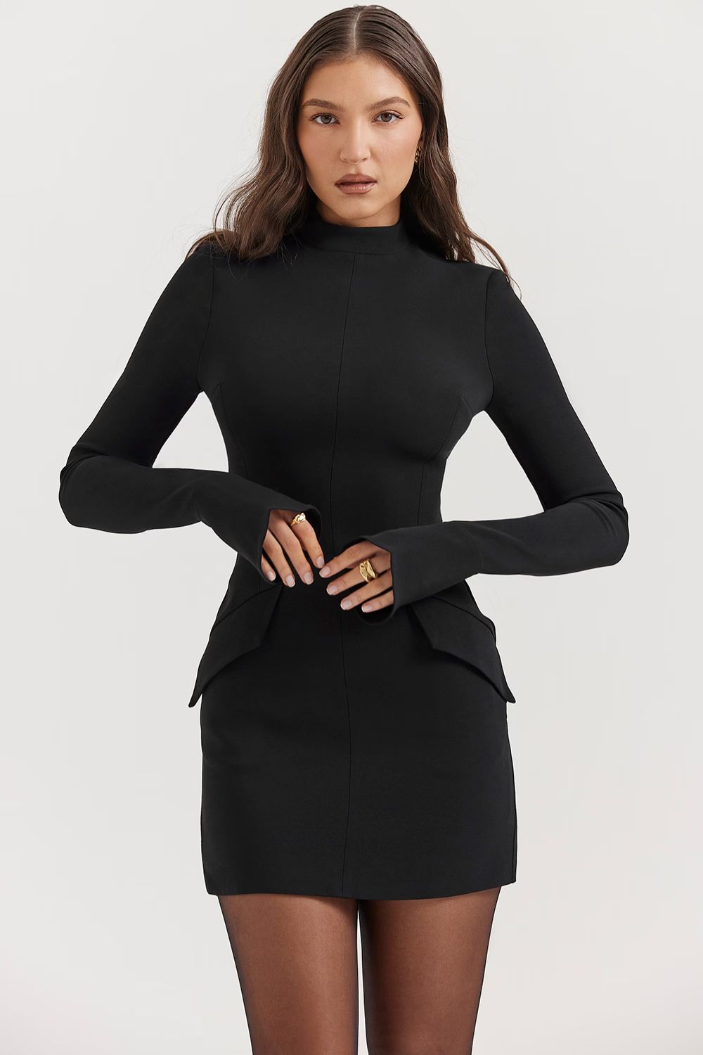 Black structured mini dress with long sleeves and mock neck, featuring subtle hip pockets and cuff details.