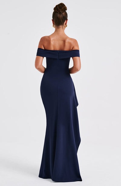Back view of a navy blue off-the-shoulder maxi dress, featuring a fitted silhouette and subtle train.