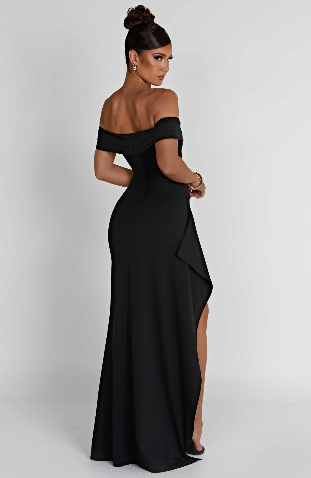 Rear side view of a black off-the-shoulder maxi dress, highlighting the fitted waist and flowing skirt.