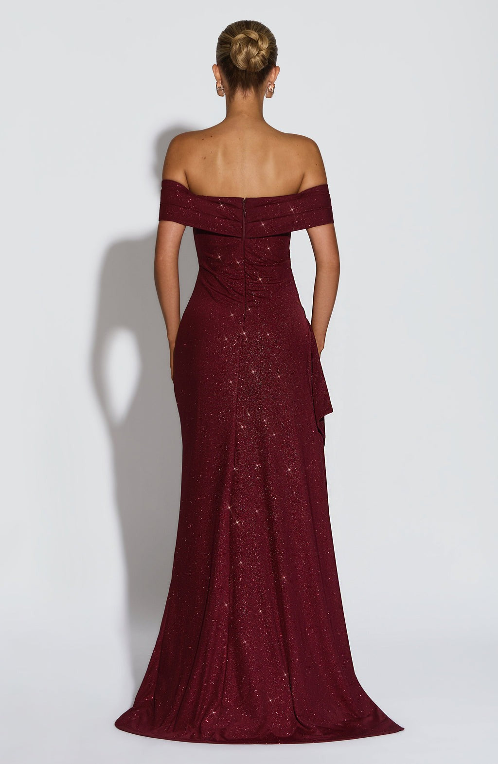 Rear view of a glittery deep red off-the-shoulder maxi dress, showing the back zipper and flowing skirt.