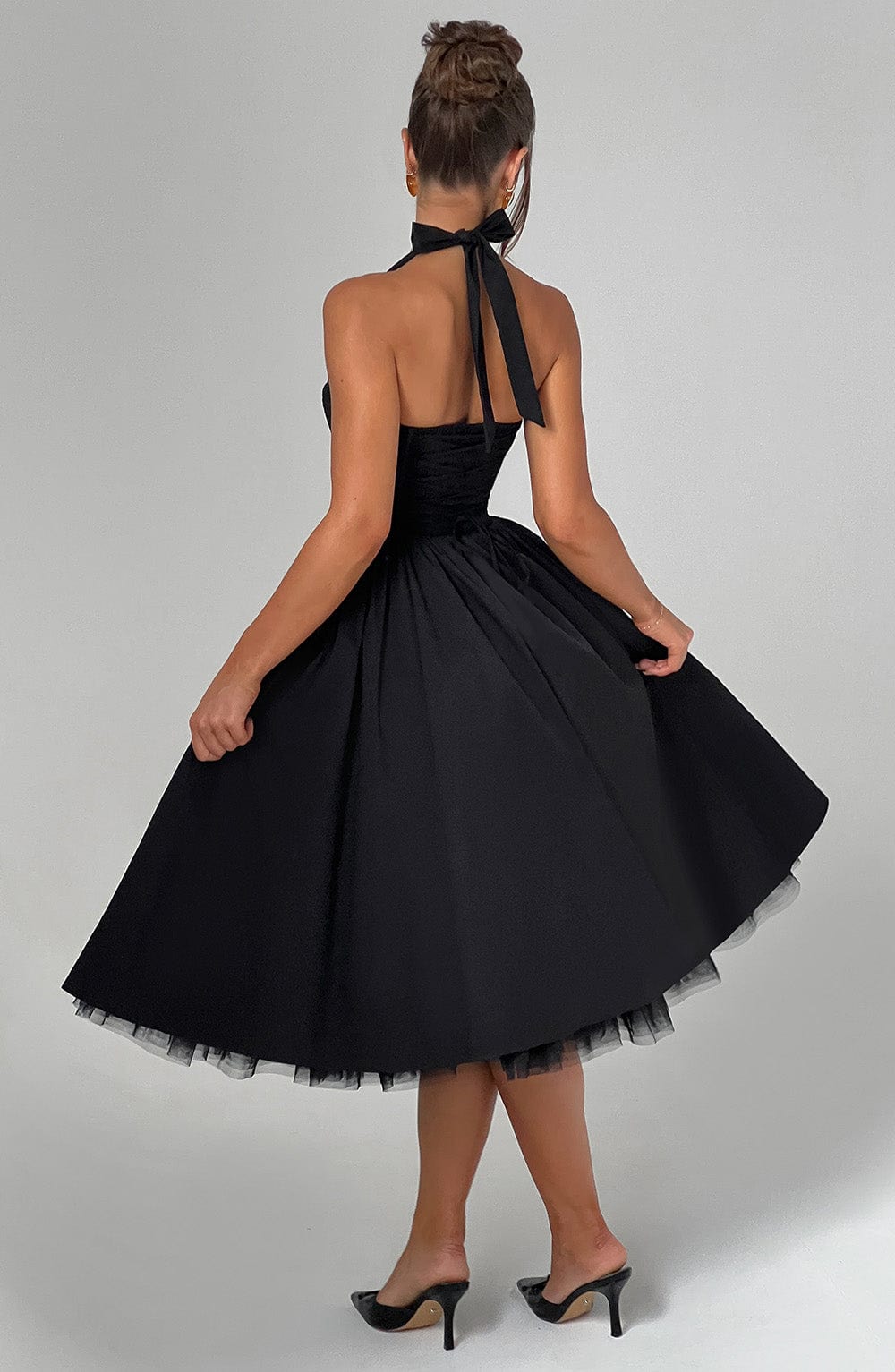 Back view of the black halter midi dress, showing the tied halter straps and the full, twirling skirt with tulle.