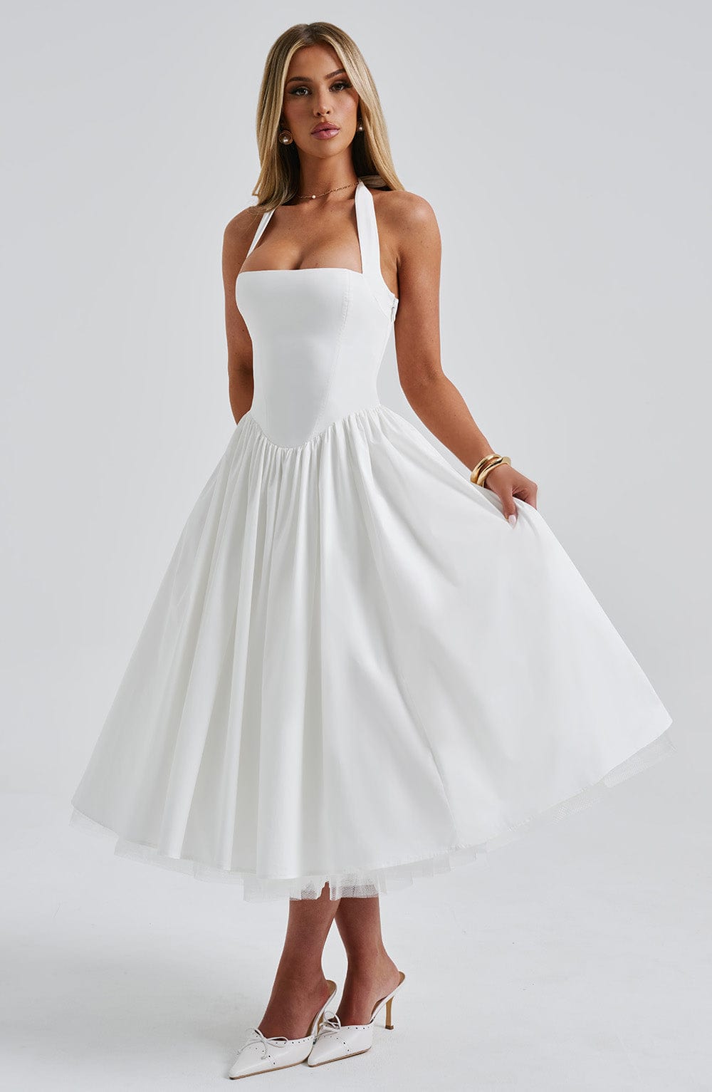Elegant white halter midi dress with a gathered waist and full skirt, showcasing the soft fabric movement.