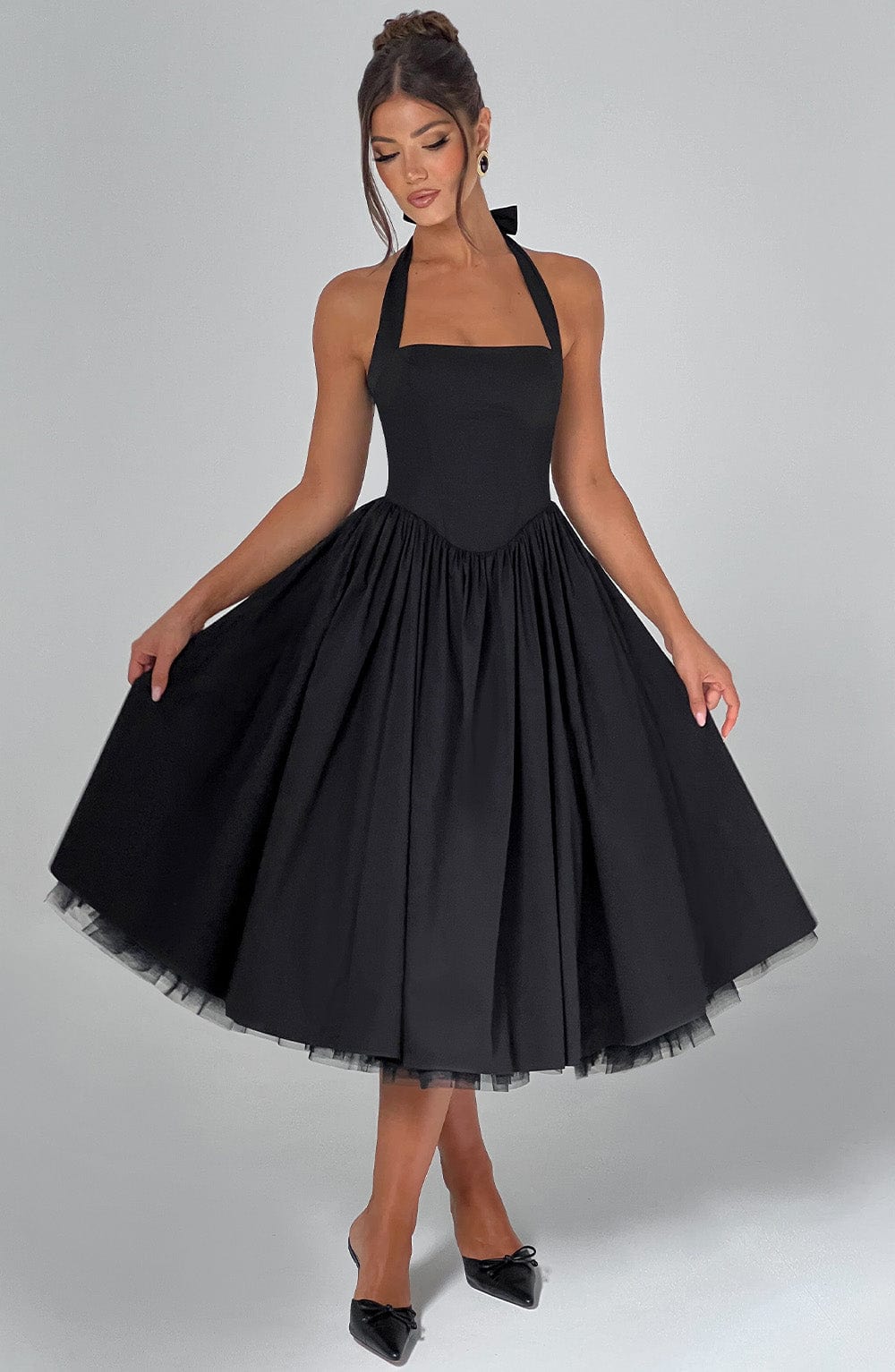 Black halter midi dress with a full, pleated skirt and a visible black tulle underskirt, perfect for an evening dress.