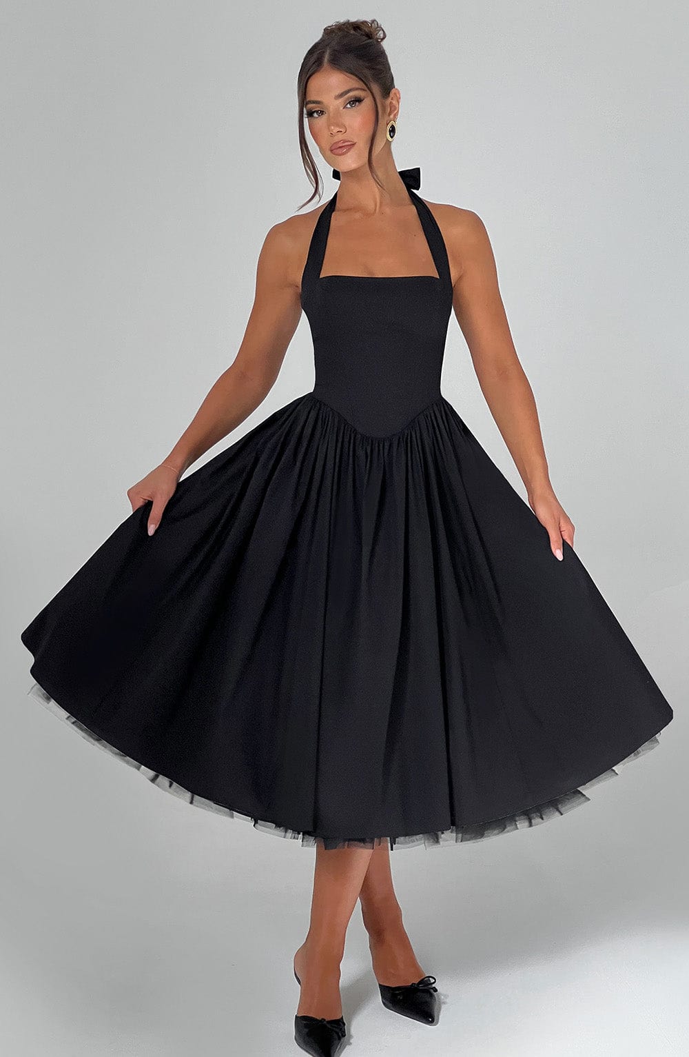 Black halter midi dress with a wide, flowing skirt, highlighting the elegant drape and movement of the fabric.