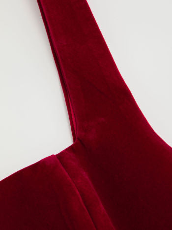 Close-up detail of the shoulder strap and square neckline of the Lillie Bow Mini Dress in red velvet, showing the plush fabric.