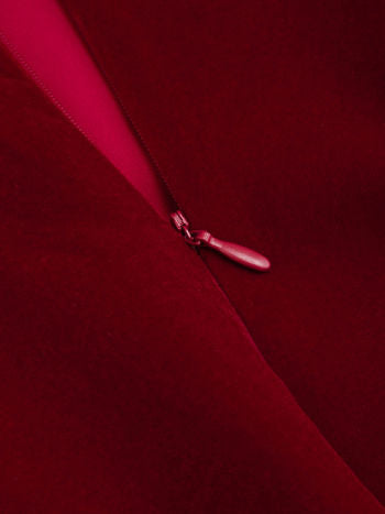 Close-up of the hidden zipper closure on a rich red velvet Lillie Bow Mini Dress, showing the zipper pull.